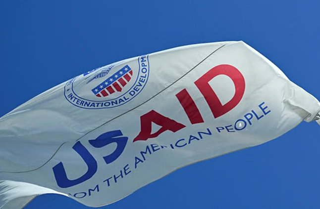 USAID and American flags waving against blue sky